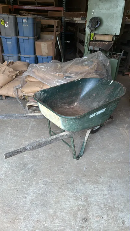 True Temper metal wheelbarrows. Features steel trays, wooden handles, and single front wheels. Contents not included.