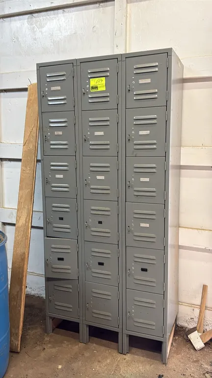 18-compartment metal employee locker unit. Features 3-wide, 6-tier configuration with 18 louvered doors, padlock hasp latches, integrated label holder