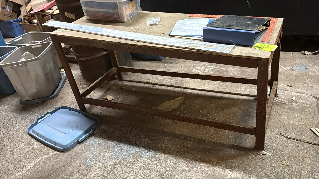 Metal framed workbench. Features a wood top and steel frame with lower support stretchers. 5'L x 2'W x 2'H. Contents not included.