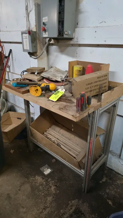 Wood top workbench with metal frame. Features an extruded aluminum frame and lower shelf support. Includes assorted tools and contents on and below th