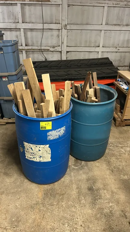 Poly barrels filled with an assortment of hardwood planks and lumber cutoffs. Features open-top molded polyethylene drum construction.