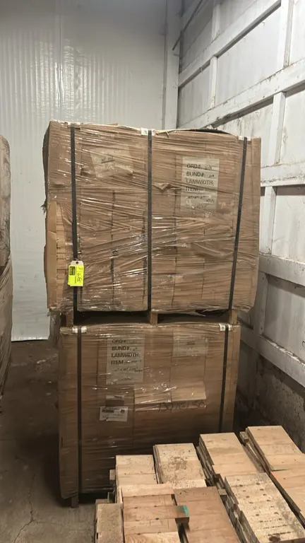 Assorted hardwood lumber bundles. Features stacked, banded, and stretch-wrapped wood stock. Palletized for transport.