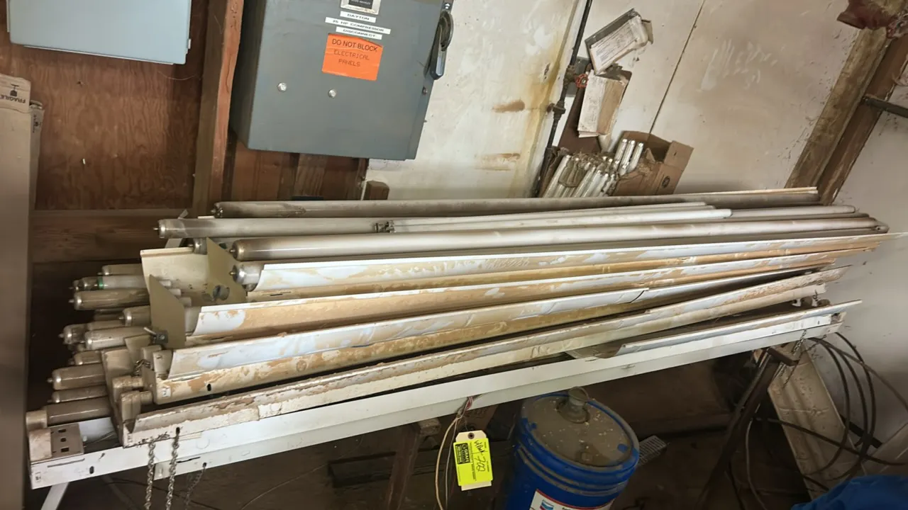 Package lot including a metal rack with fluorescent light fixtures and an assortment of fluorescent light bulbs. Includes long tube fixtures and boxed