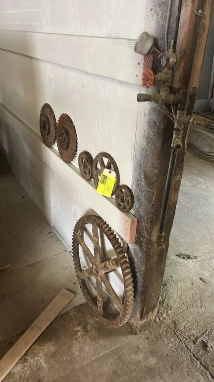 Cast-iron industrial gears and cogs. Assorted sizes and styles including spoked gears and toothed wheels. Cast-iron construction.