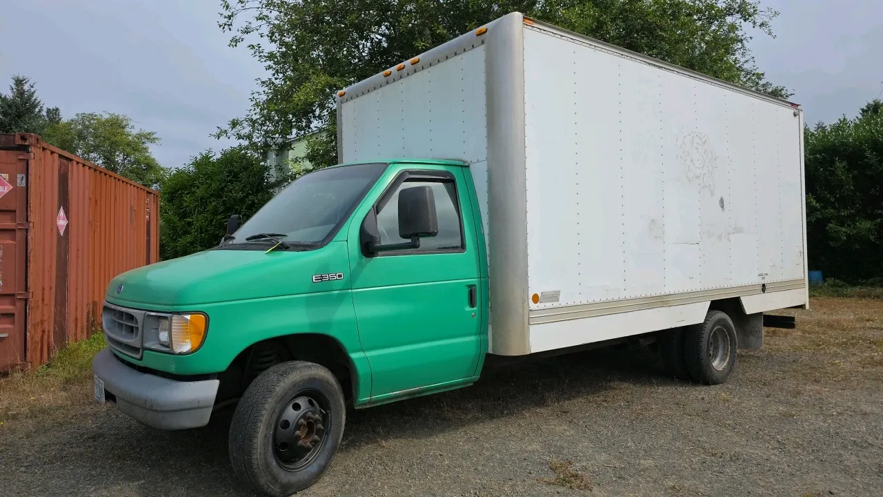 1997 Ford E-350 box truck. Features a 7.3L Power Stroke turbo diesel engine, automatic transmission, roll-up rear door, pull-out aluminum ramp, and tr