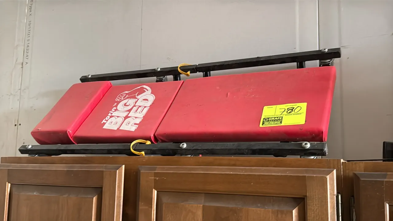 Torin Big Red mechanic creeper. Features padded red vinyl cushions and black metal frame. Mounted on swivel casters.