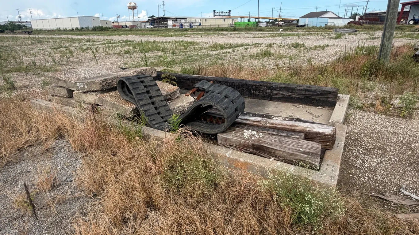 PILE OF CONCRETE PAVERS, WOOD, AND RUBBER TRACKS