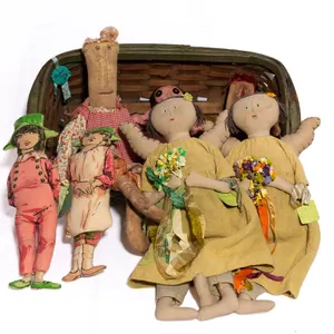 GREEN WOVEN BASKET WITH PRIMITIVE AND FOLK ART DOLLS.