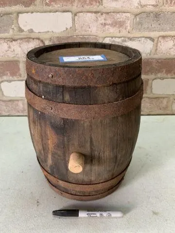 SMALL WOODEN BARREL WITH RUSTED BANDS AND A