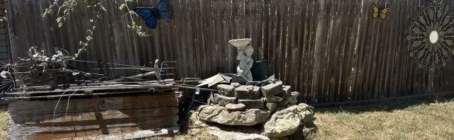 SELECTION OF YARD DECOR ITEMS ON AND IN FRONT OF