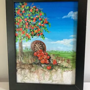 Framed acrylic painting depicting an apple tree with red apples and a basket tipped over on the grou