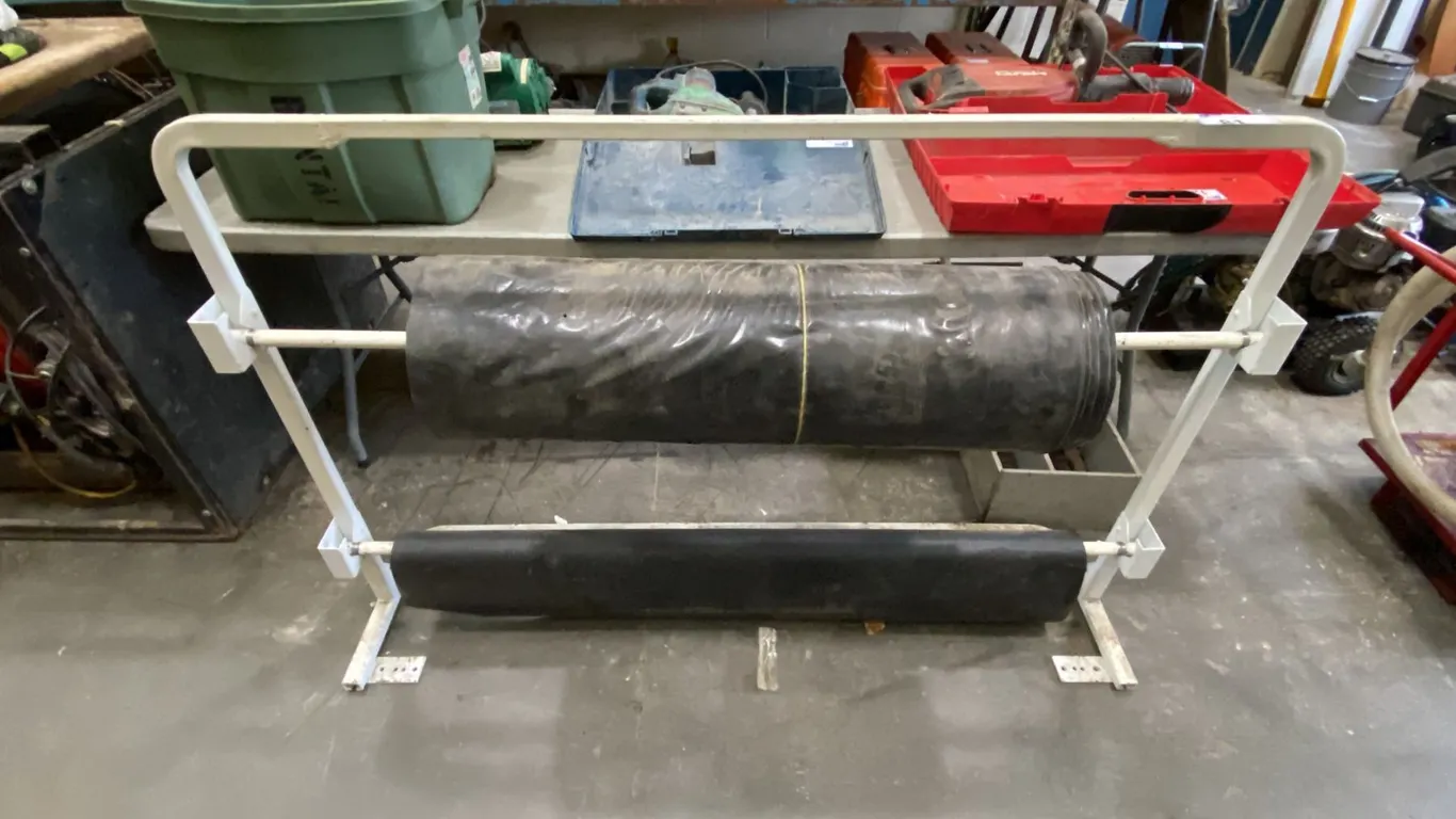 WHITE DUAL ROLL MATERIAL STAND WITH A PARTIAL ROLL OF LUMBER WRAP & LARGE ROLL OF BLACK POLY WRAP