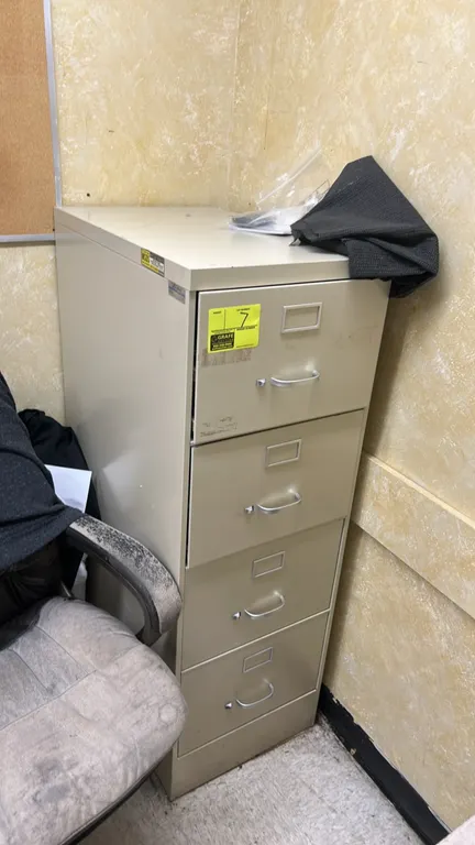 Metal 4-drawer vertical filing cabinet. Features four pull-out drawers with bow handles and integrated label holders. Putty/beige finish. Contents not