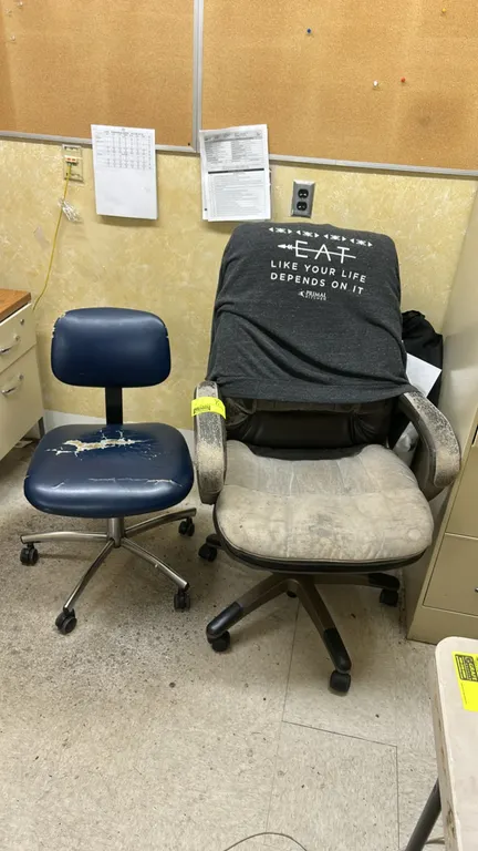 Rolling office chairs. Includes (1) blue vinyl task chair and (1) upholstered executive chair. Each mounted on a 5-star rolling caster base. Note: Uph