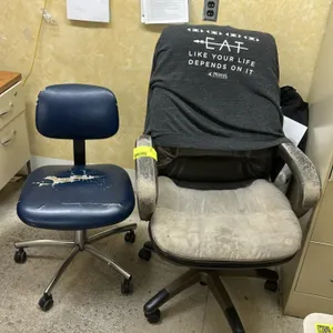 Rolling office chairs. Includes (1) blue vinyl task chair and (1) upholstered executive chair. Each mounted on a 5-star rolling caster base. Note: Uph