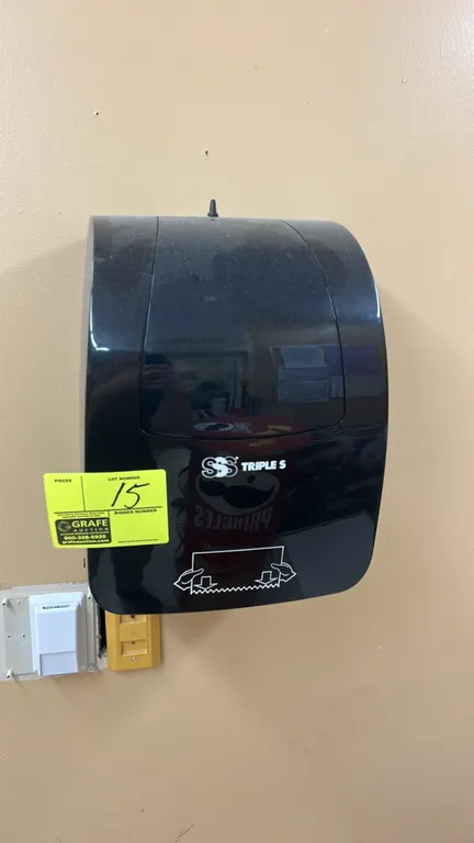 Triple S paper towel dispenser. Features black plastic housing and manual bottom feed design. Wall-mounted.