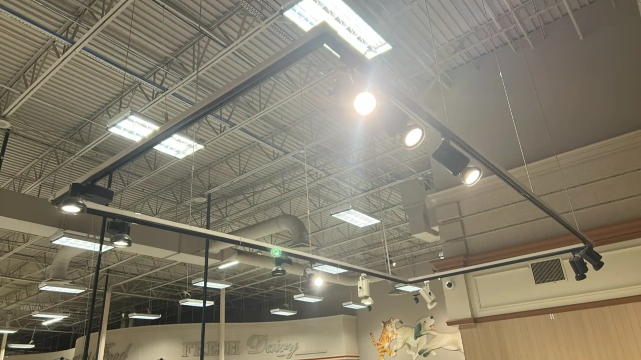 Suspended track lighting system. Includes ceiling-suspended linear track layout with multiple adjustable track lighting spotlight fixtures in black an