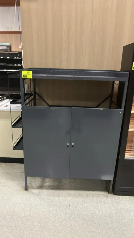 Metal multi-tier display rack cabinet. Features a 2-door lower storage compartment, top storage tier, and side-mounted 4-tier wire basket shelving. Gr