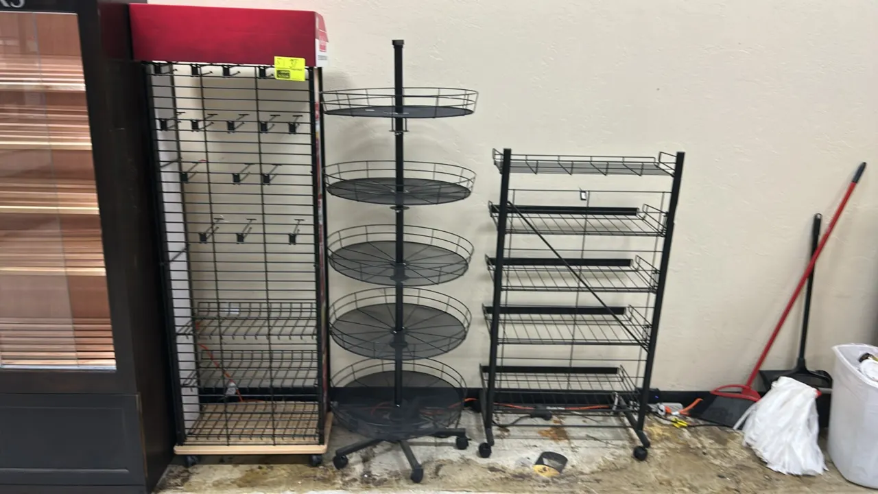 Metal mobile multi-tier display merchandisers. Includes (1) grid tower rack with hanging hooks, lower wire baskets, and header; (1) 5-tier round rotat