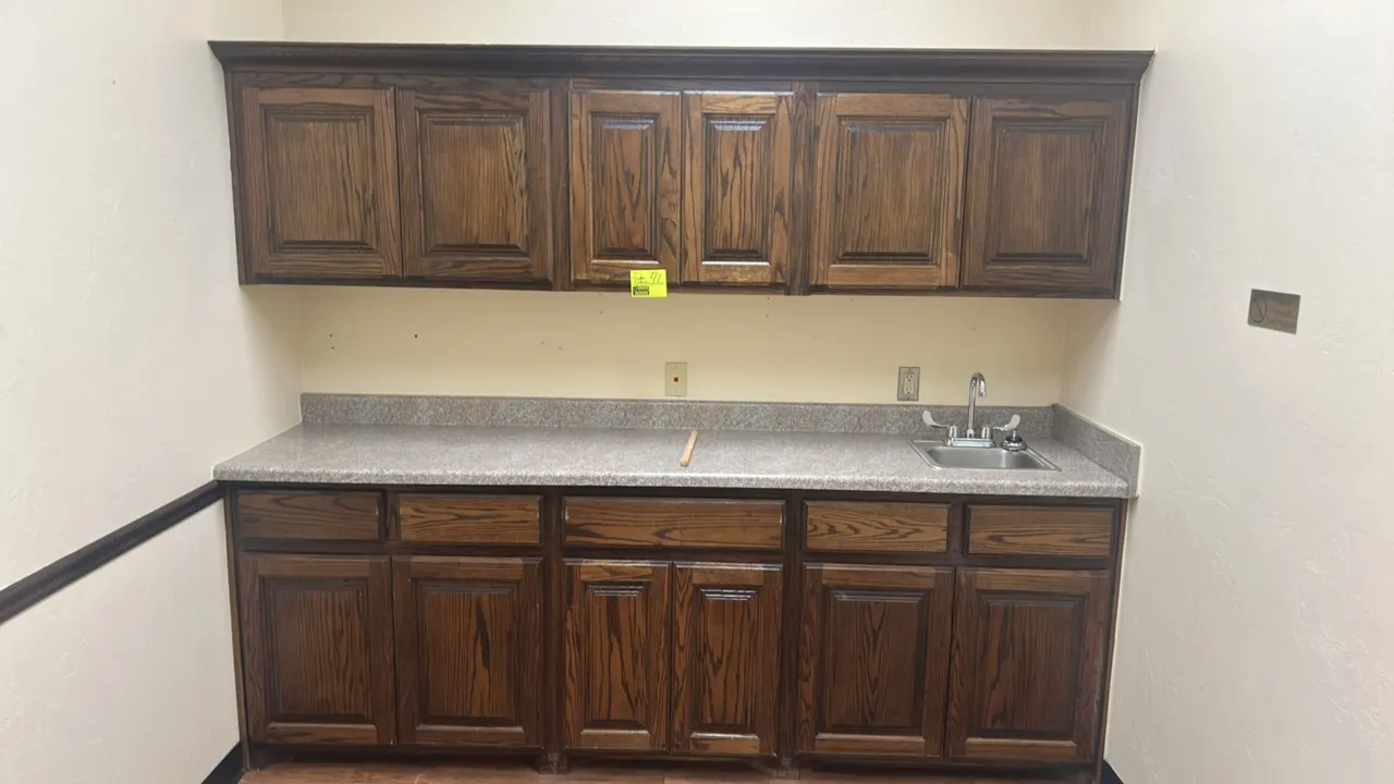 8' laminate countertop with upper and lower cabinets and stainless steel sink. Features woodgrain finish cabinetry, single-basin stainless steel drop-