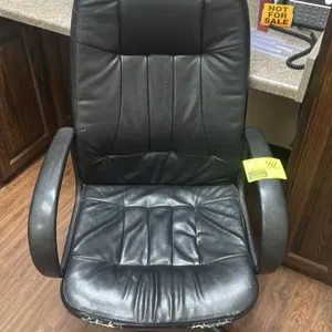Cushioned executive office chair. Features black upholstered high back and seat with fixed armrests. Mounted on a 5-star swivel base with casters. Not