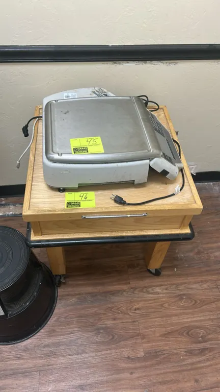 Wooden mobile table. Features raised edge trim on tabletop, bumper guard perimeter, and front pull handle. 2'L. Mounted on swivel casters. Scale and b