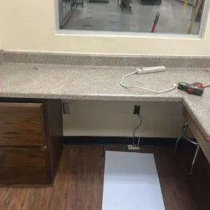 L-shaped laminate countertop with base and wall cabinets. Features speckled faux-stone laminate countertop with integrated backsplash, woodgrain finis