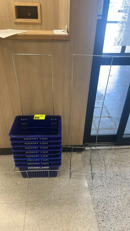 Poly shopping baskets. Features blue plastic construction, black folding handles, and Homeland branding. Includes (2) wire metal floor stands.
