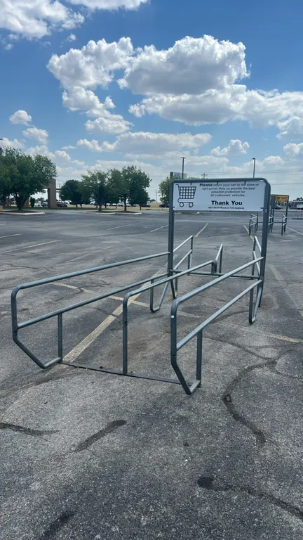 Metal shopping cart corrals. Features tubular metal construction, dual-lane design, and an integrated overhead sign frame with return cart signage. 64