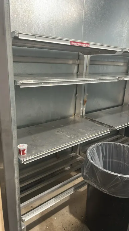 Aluminum cantilever shelving rack. Features multi-tier solid aluminum upper shelves, a slatted aluminum base shelf, and integrated shelf label channel