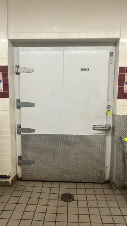 Tyler walk-in cooler. Features foam insulated panels, pallet-sized door with diamond plate kickplate, Tyler 3-fan evaporator coil, strip curtain, and