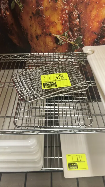 Stainless steel wire cooling racks. Features wire grid construction with integrated feet in assorted sizes. Cart, cutting boards, and other background