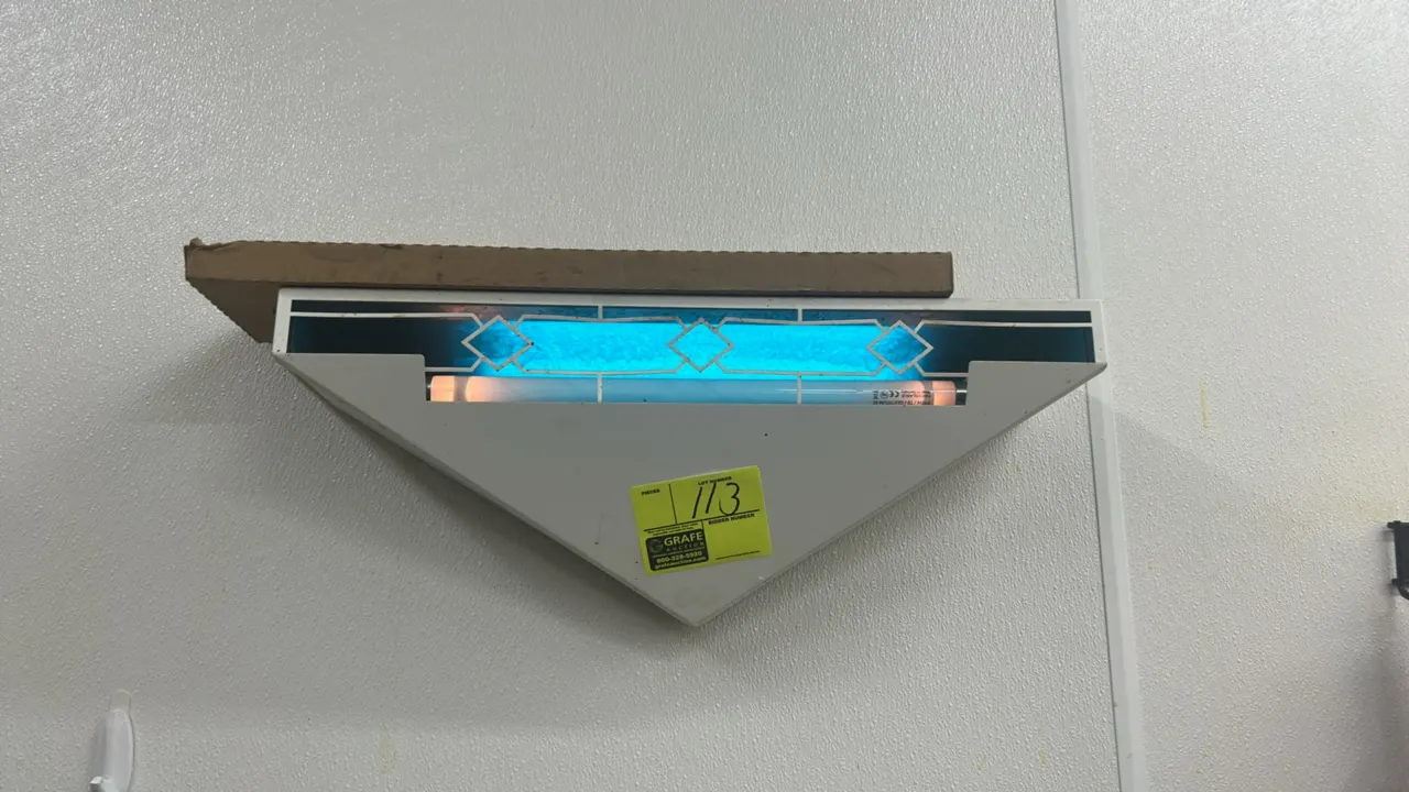 Wall-mounted insect light trap sconce. Features a white metal triangular housing with a decorative cutout front panel and UV tube light. Wall-mount de