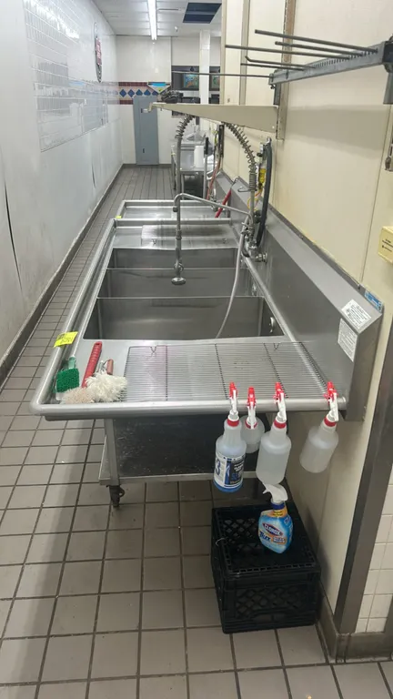 Stainless steel 3-compartment sink. Features left and right drainboards, integrated backsplash, pre-rinse spray assembly, and tubular stainless steel