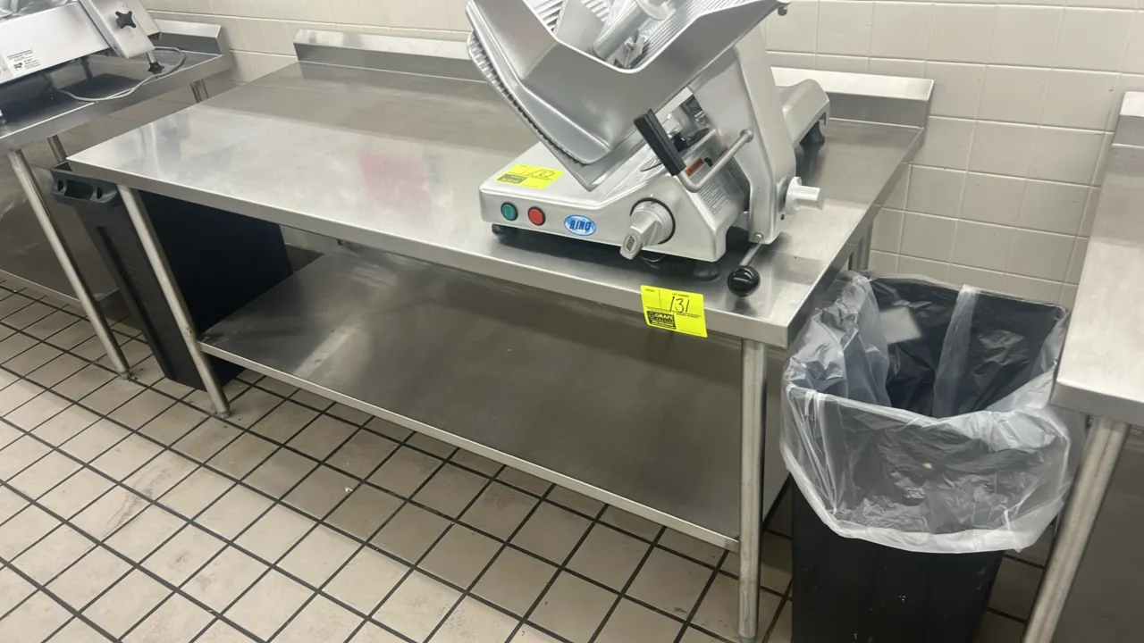 Stainless steel work table. Features a rear backsplash and lower undershelf. Mounted on tubular legs with adjustable bullet feet. Dimensions: 72"L x 3