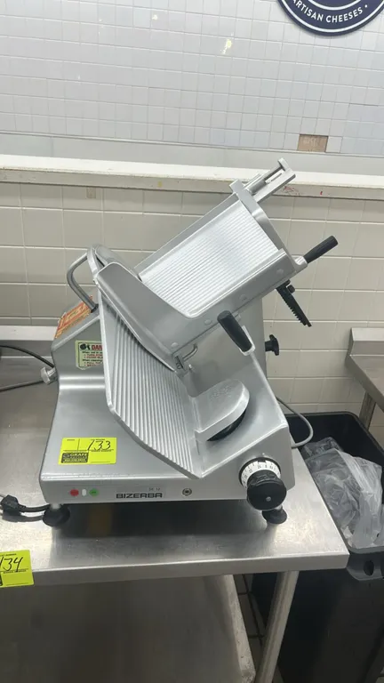 Bizerba SE 12 deli meat slicer. Features anodized aluminum construction, gravity-feed angled product carriage with product pusher, adjustable slice th