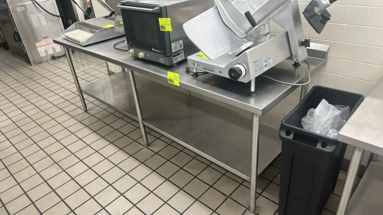 Stainless steel work table. Features a rear backsplash, lower undershelf, and tubular legs with adjustable bullet feet. 96" x 30". Tabletop equipment