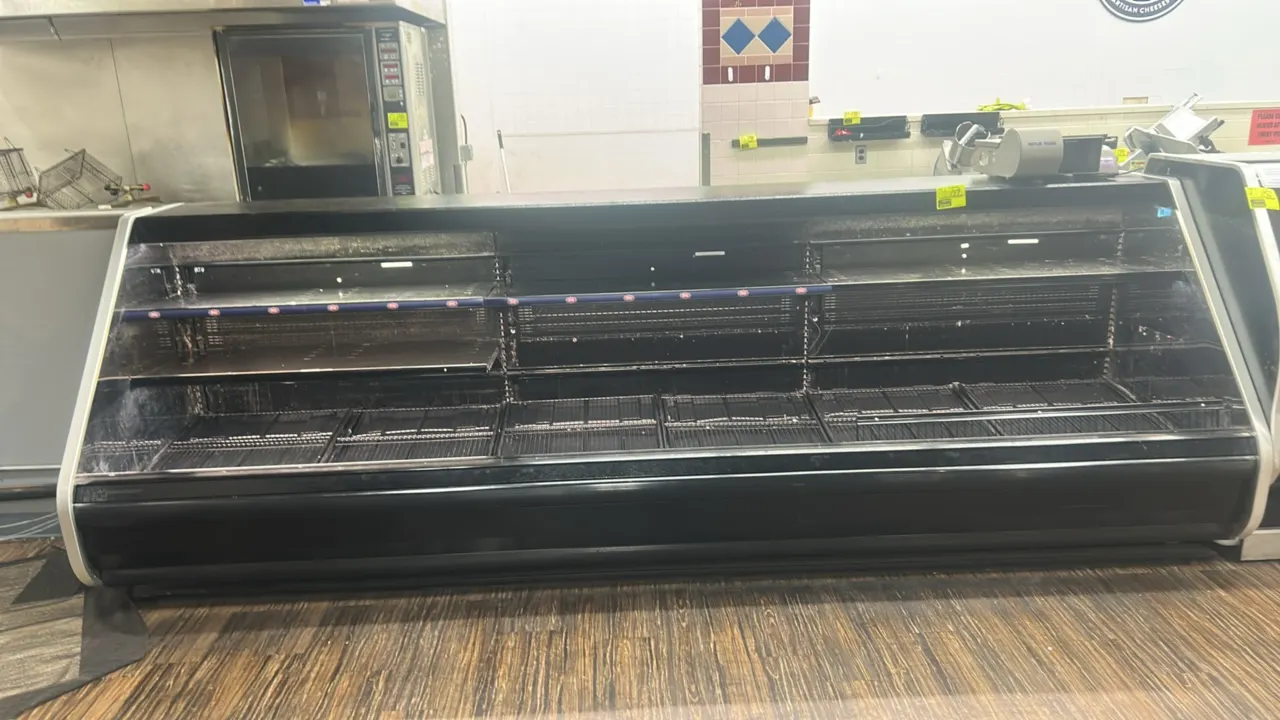 Hussmann medium-temp open deli grab and go display case. Features multi-tier shelving, bottom wire rack decking, black exterior trim, and stainless st