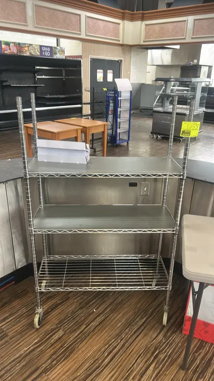 Chrome metal wire 3-tier mobile shelving rack. Features (3) wire shelves with solid liners on the top two tiers. 36"W x 14"D. Mounted on swivel caster