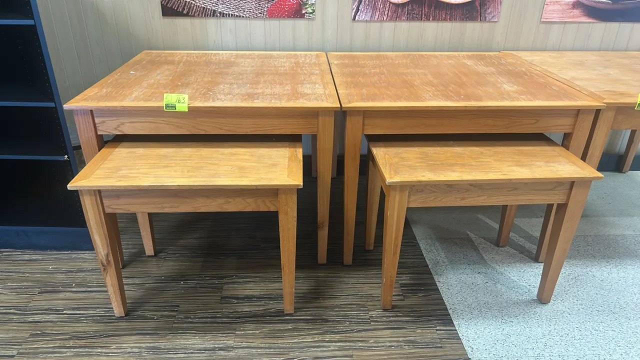 Wooden nesting table sets. Each 2-piece set features a larger display table with a smaller nesting table below. Wood construction with tapered square