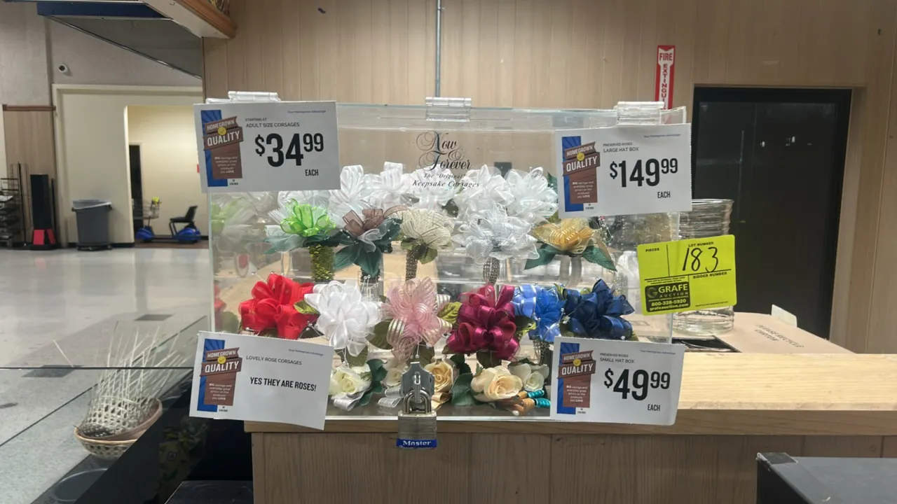Clear acrylic floral display box. Features hinged top lid, front locking hasp with padlock, and interior corsage display holders. Countertop placement