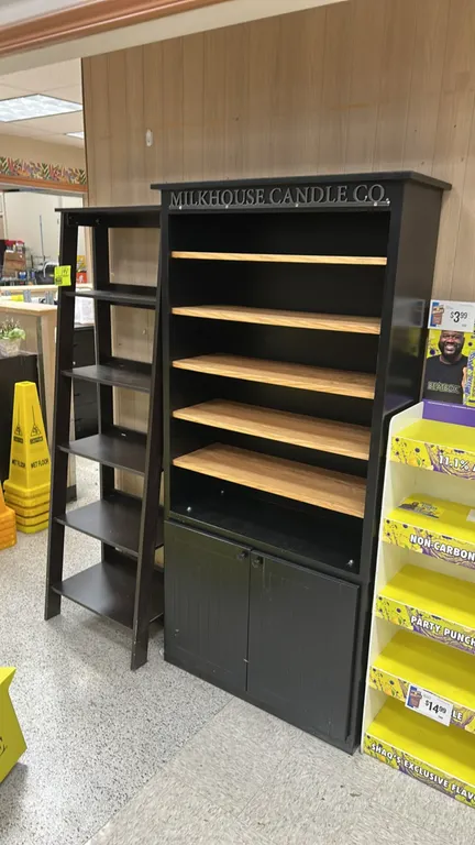 Wooden merchandising display shelves. Includes (1) Milkhouse Candle Co. branded display cabinet featuring 5 wood-tone shelves and a 2-door lower stora