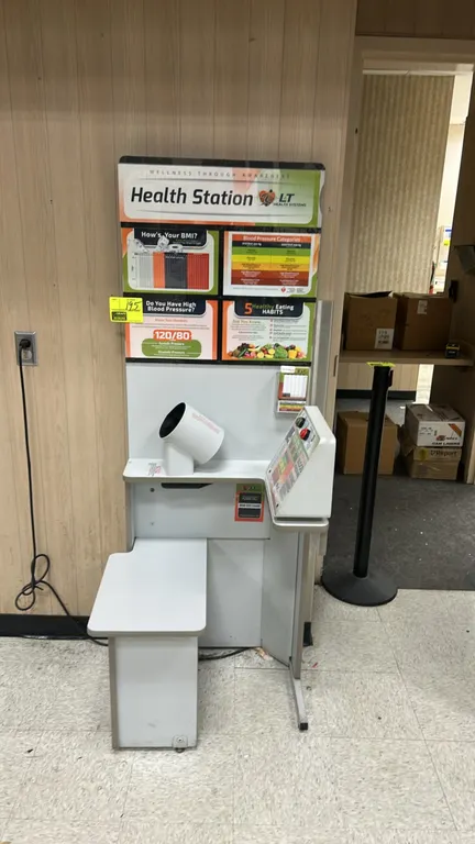 LifeClinic blood pressure kiosk. Features automated arm cuff, digital display console for systolic, diastolic, and pulse rate readings, integrated ben