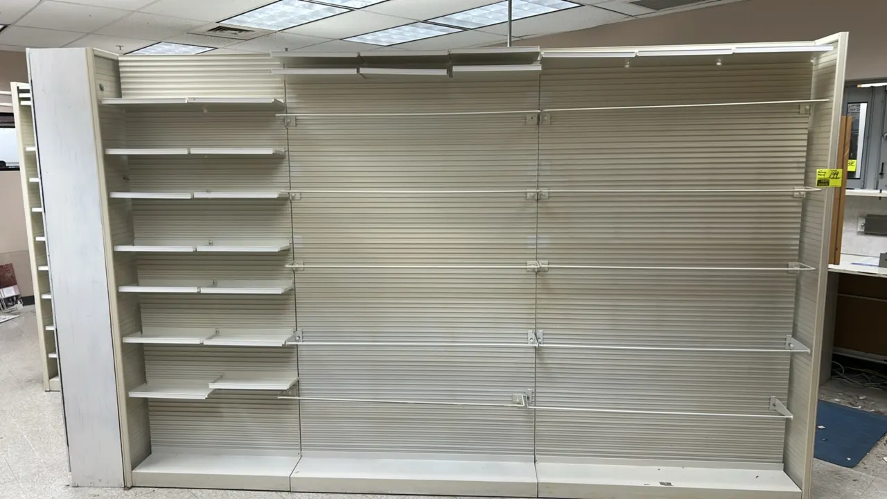 Metal pharmacy shelving. Features double-sided slatted back panels, adjustable metal shelves with label channels, slatted end panel, and retainer bars
