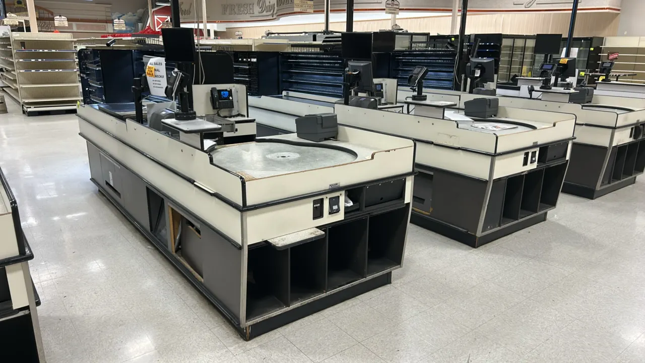Killion single belt laminate checkout lanes. Features motorized conveyor belt, rotating circular bagging turntable station, lower bag storage cubbies,