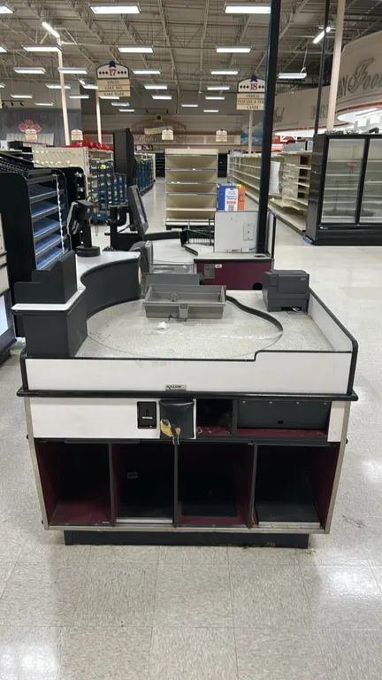 Killion laminate checkout lane. Features rotating circular bag station, white and burgundy laminate finish with protective bumper rails, and lower sto