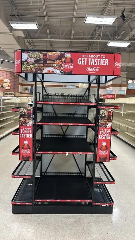 Metal 3-sided multi-tier retail merchandiser display. Features Coca-Cola branded header and side graphic panels, multi-tier black wire shelves, and bl