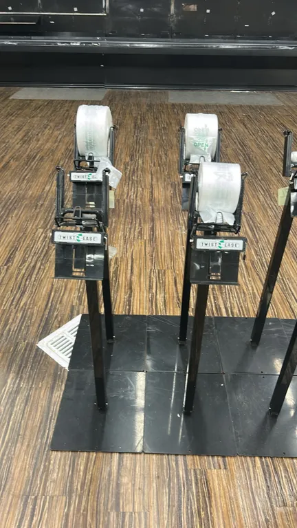 Twist-Ease metal bag dispenser stands. Features black metal construction with flat floor base plates, roll bag cradles, and integrated Twist-Ease twis