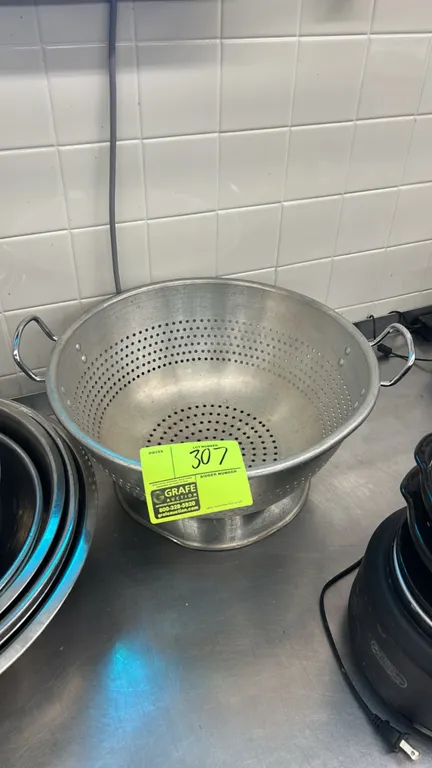 Metal colander with poly colander. Includes 16" metal colander with dual side loop handles and footed base, and a green plastic colander.
