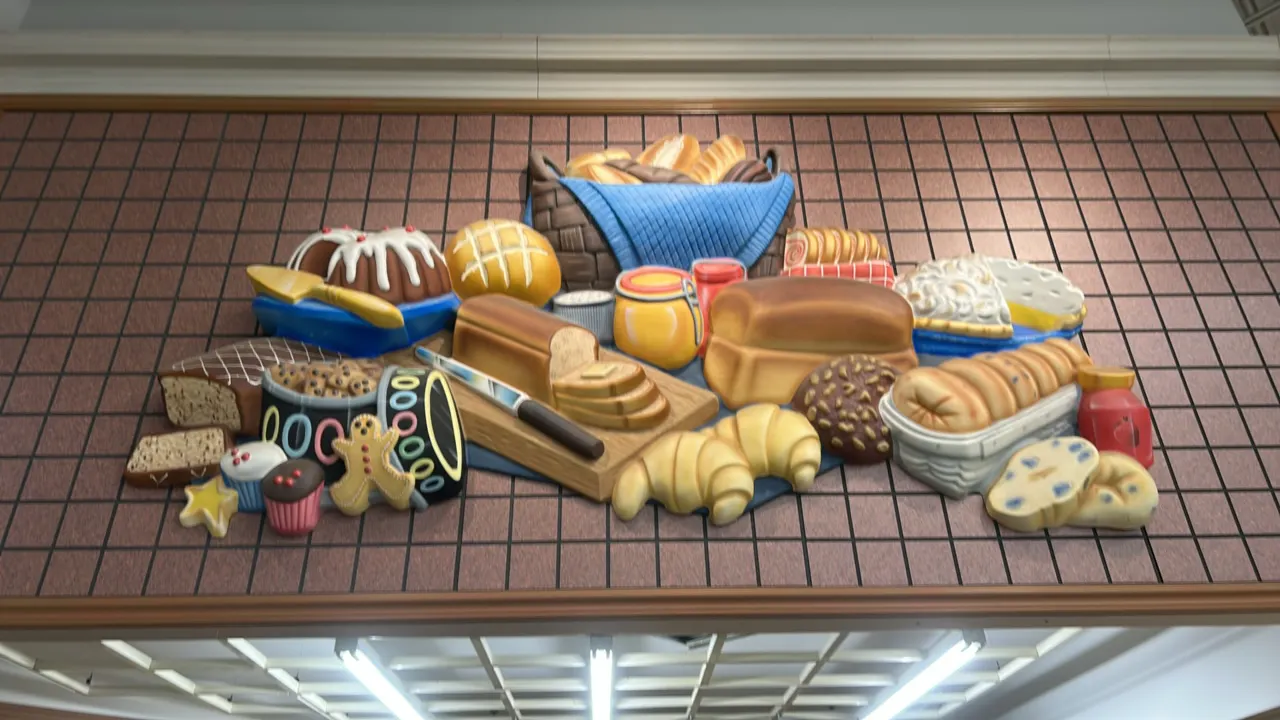 Bakery 3D relief wall decor displays. Features dimensional molded bakery assortment including bread loaves, croissants, bundt cake, pies, cupcakes, an